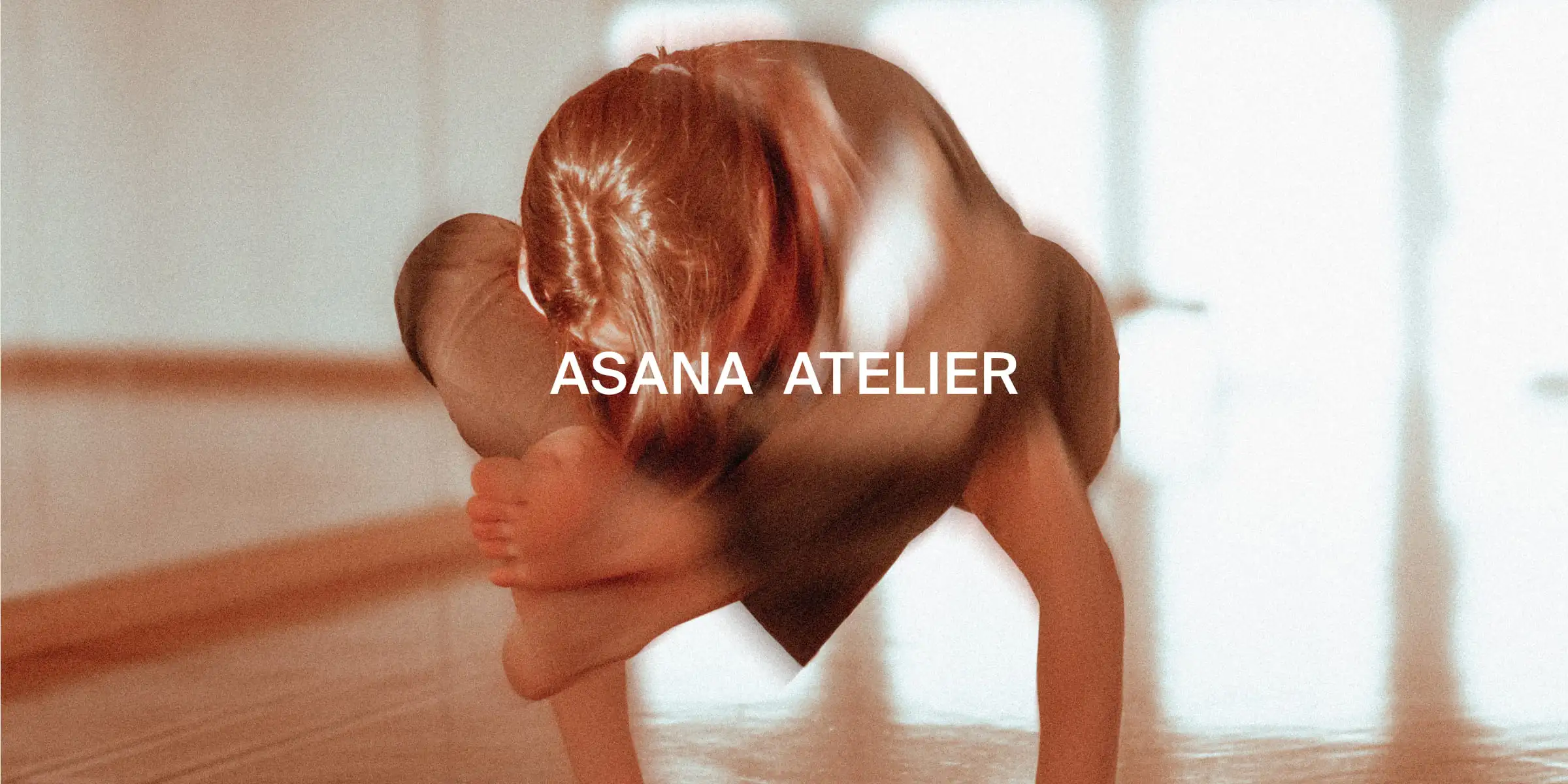 Nahaufnahme einer Person, die eine Armbalance-Yoga-Pose in einem Yoga Studio mit dem Text „ASANA ATELIER“ übt.